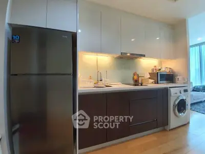 Modern kitchen with sleek cabinetry, stainless steel fridge, and washing machine