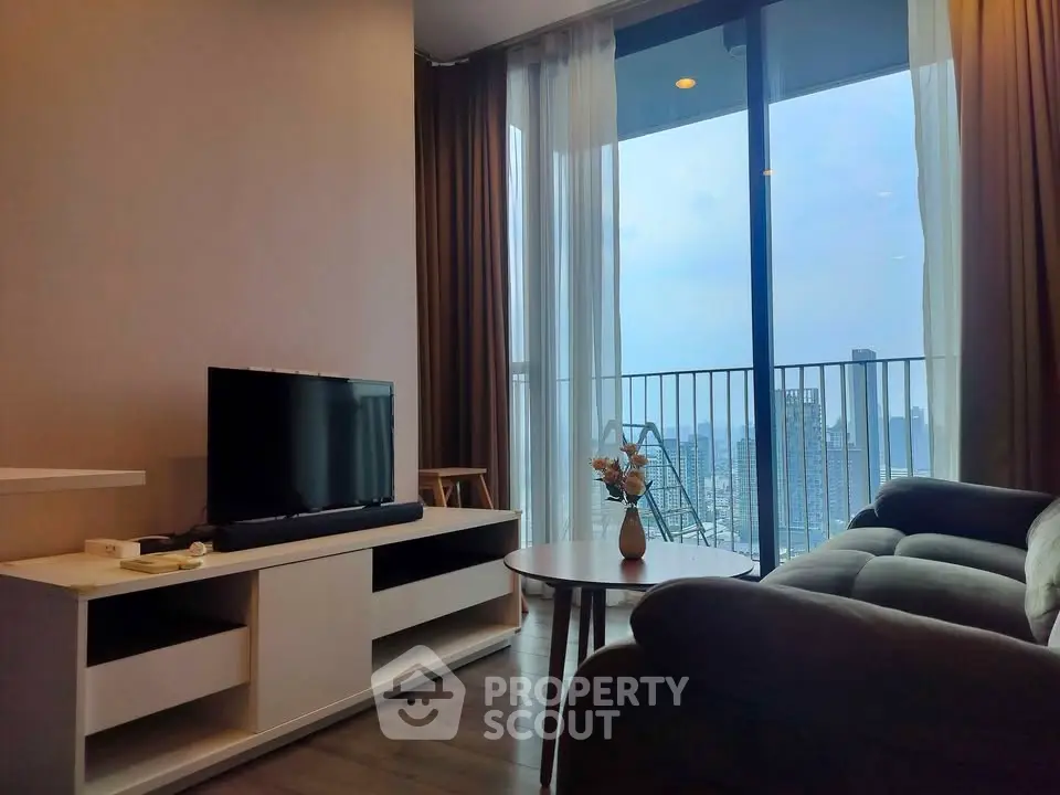 Modern living room with city view and balcony access, featuring sleek furniture and large windows.