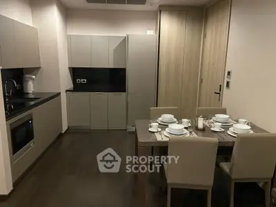 Modern kitchen with sleek cabinetry and dining area set for four, featuring elegant tableware.