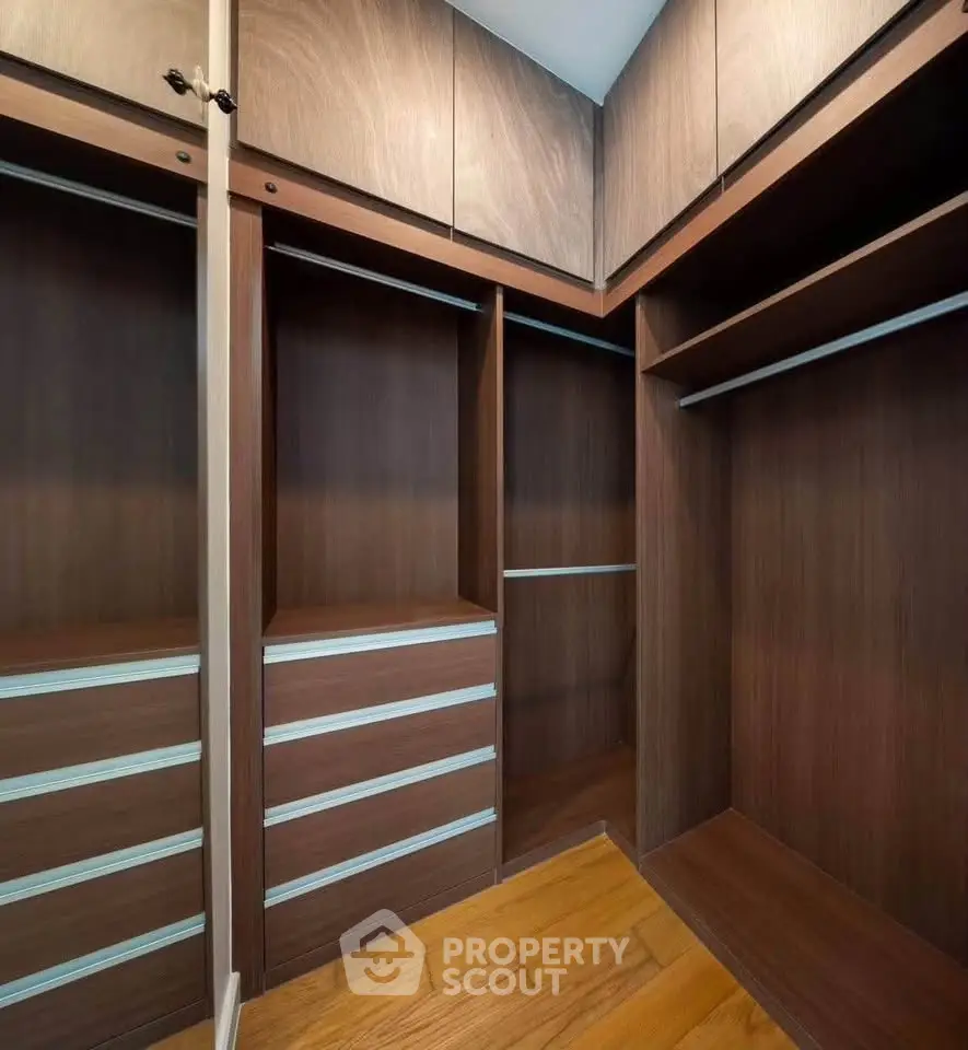 Spacious walk-in closet with elegant wooden finish and ample storage space.