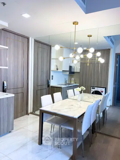 Modern dining area with elegant chandelier and mirrored wall in a stylish apartment