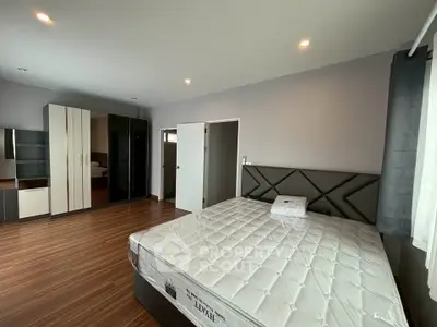 Spacious bedroom with modern furnishings and ample natural light, featuring a large bed and sleek wardrobe.