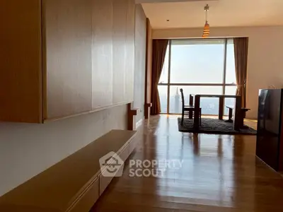 Spacious living room with wooden flooring and large window offering stunning city view.
