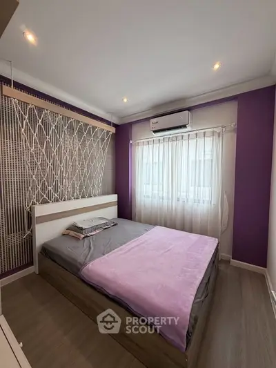 Modern bedroom with stylish decor and natural light, featuring a cozy bed and air conditioning.