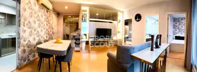 Modern open-plan living room with stylish decor and adjacent kitchen, featuring elegant dining area and cozy seating.