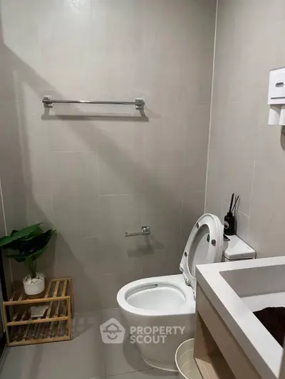Modern bathroom with sleek fixtures and minimalist design, featuring a toilet, sink, and towel rack.