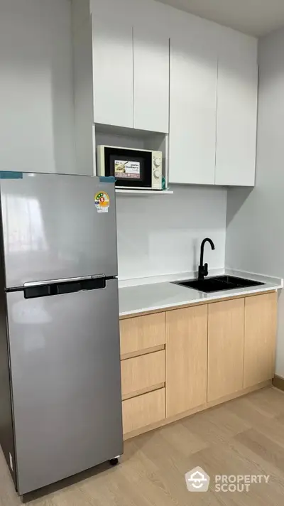 Modern compact kitchen with sleek cabinetry and stainless steel fridge