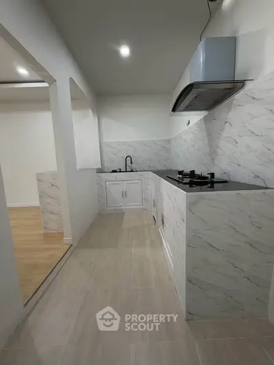 Modern kitchen with sleek marble countertops and gas stove in a stylish open layout.