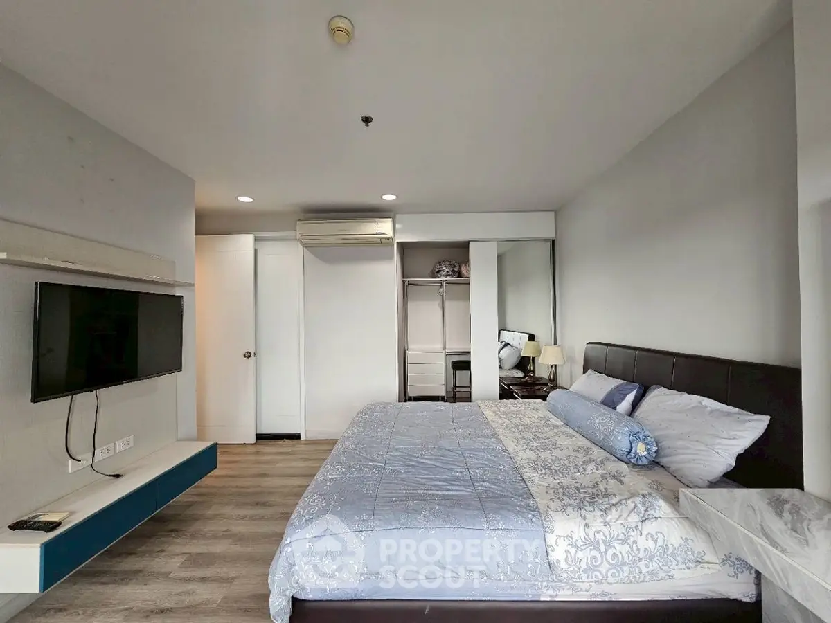 Spacious bedroom with modern decor and wall-mounted TV in a stylish apartment.