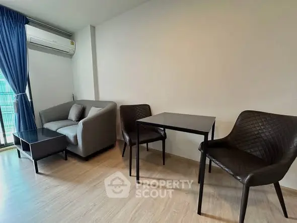 Modern living room with sleek furniture and natural light from balcony window.
