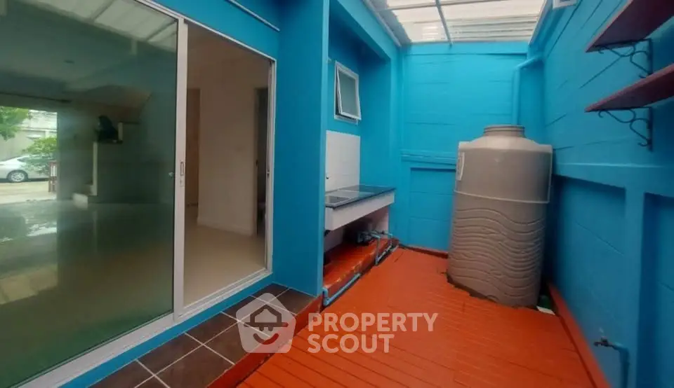 Vibrant outdoor utility area with water tank and bright blue walls