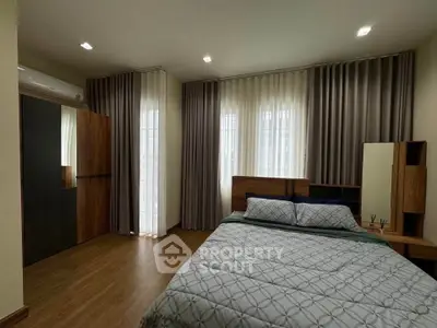 Spacious bedroom with modern decor and large windows for natural light.