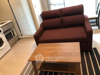 Cozy living room with modern sofa, wooden coffee table, and washing machine in compact space.