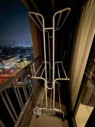 City view from high-rise balcony with drying rack at night