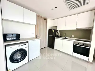 Modern kitchen with sleek white cabinets, washing machine, and built-in oven in a stylish apartment.