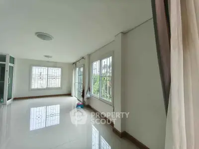 Spacious and bright living room with large windows and elegant tile flooring.