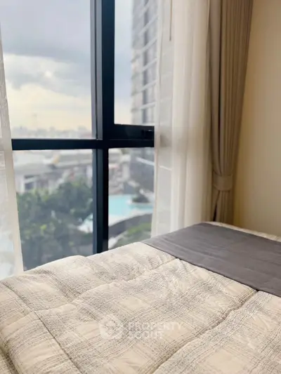 Cozy bedroom with large window offering a stunning view of the cityscape and pool area.