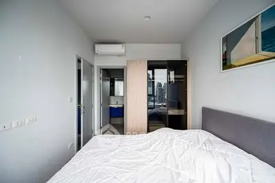 Modern bedroom with city view and ensuite bathroom in high-rise apartment.