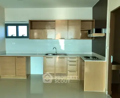 Modern kitchen with sleek wooden cabinets and built-in stove, perfect for culinary enthusiasts.