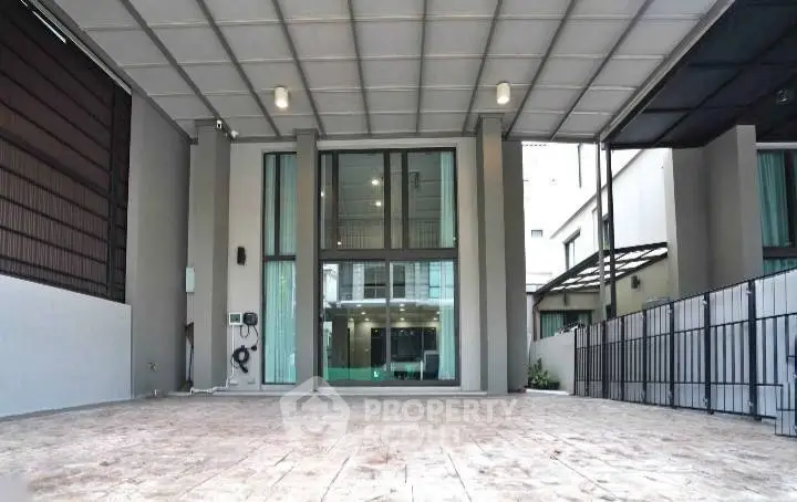 Spacious modern building entrance with covered parking area and large windows.
