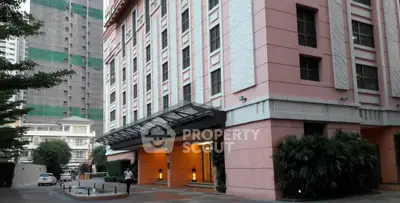 Elegant pink building exterior with modern entrance and lush greenery