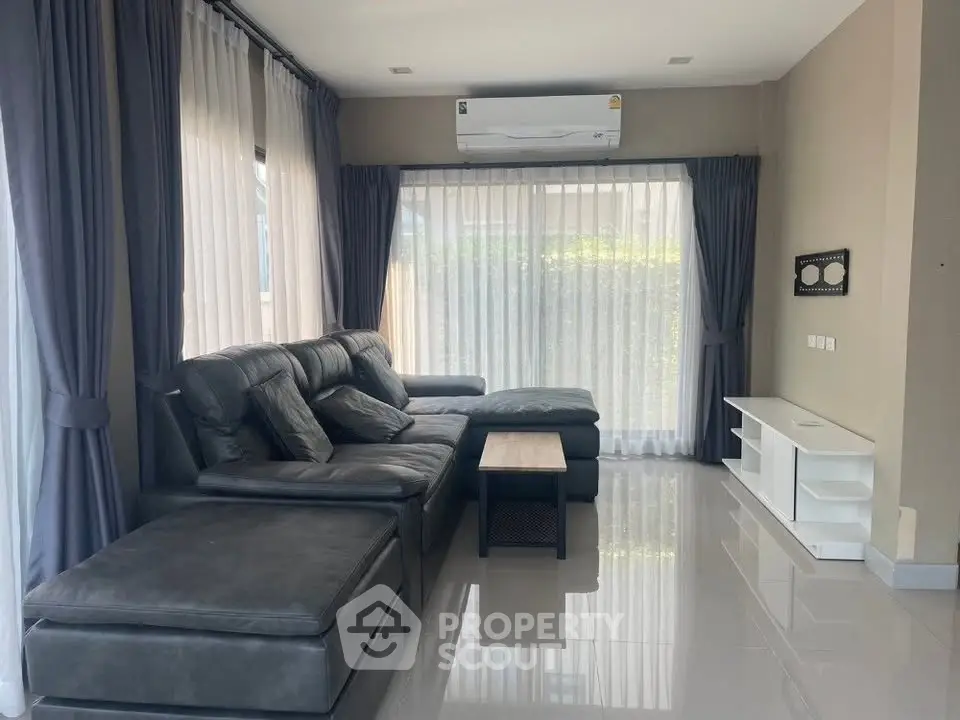 Spacious living room with modern leather sofa and large windows for natural light.
