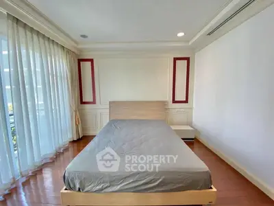 Spacious bedroom with large windows and elegant wooden flooring