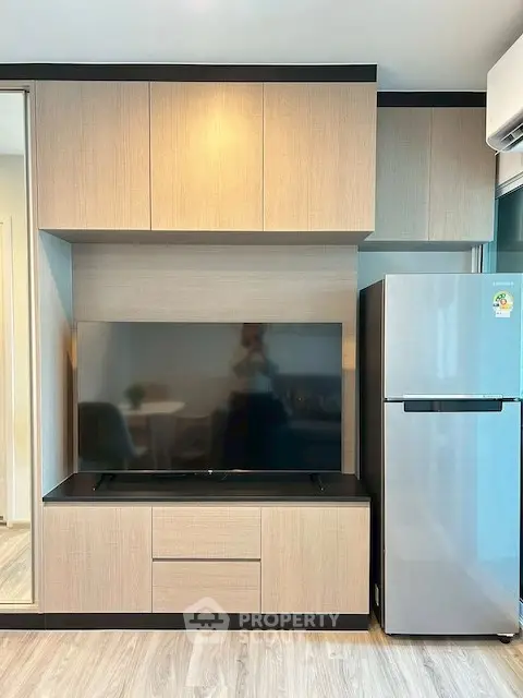 Modern living room with sleek TV unit and stainless steel fridge