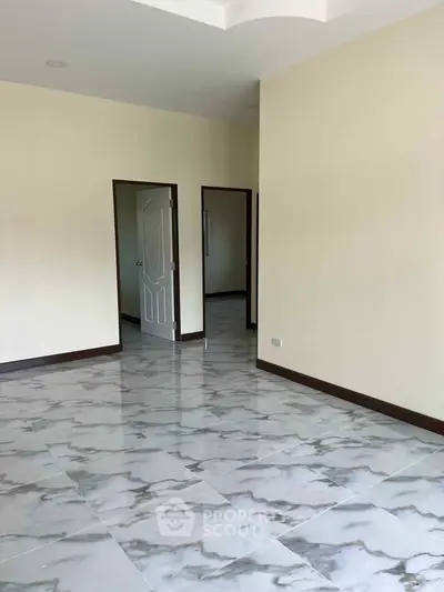 Spacious empty room with elegant marble flooring and neutral walls, perfect for customization.