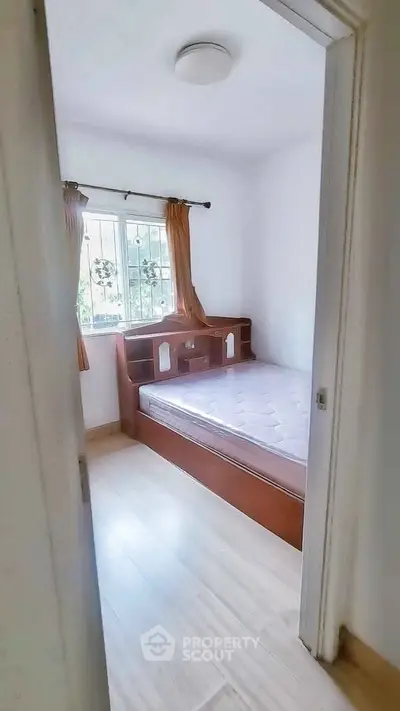 Cozy bedroom with natural light and wooden furniture, perfect for relaxation.