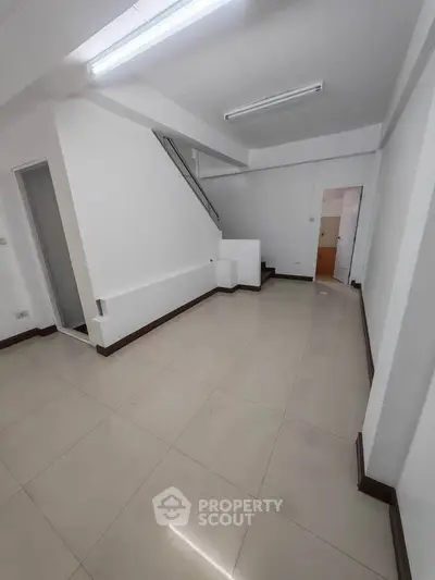 Spacious interior with modern tile flooring and staircase, ideal for versatile living space.