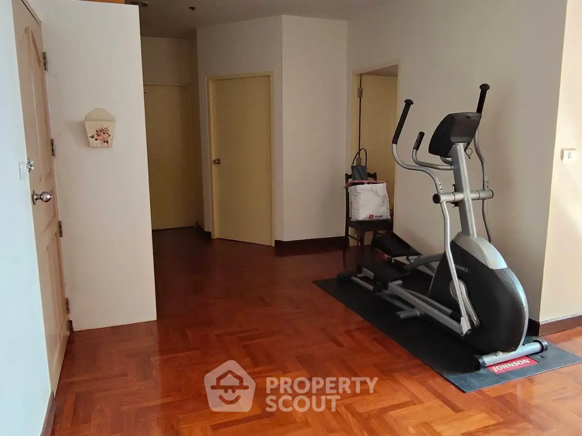 Spacious home gym area with exercise equipment and wooden flooring