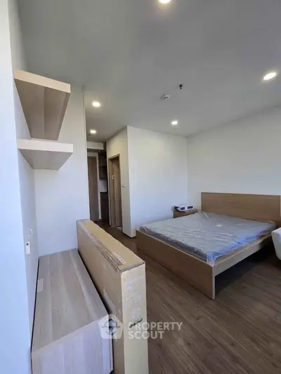 Modern bedroom with wooden flooring and minimalist furniture in a stylish apartment.