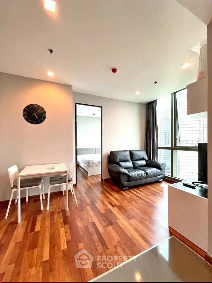 Modern living room with wooden flooring, cozy sofa, and dining area in a bright apartment.