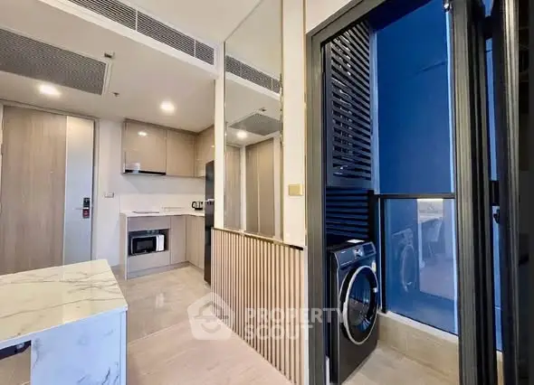 Modern apartment interior with sleek kitchen and in-unit washing machine, featuring stylish design and efficient layout.