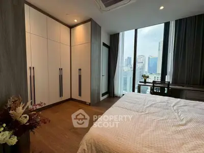 Modern bedroom with city view, featuring sleek wardrobe and cozy decor.