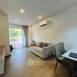 Modern living room with cozy sofa and dining area, featuring natural light and wooden flooring.
