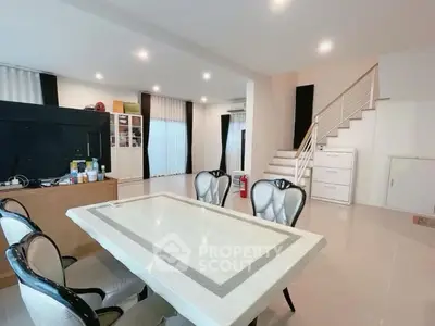 Spacious open-plan living and dining area with modern decor and staircase.