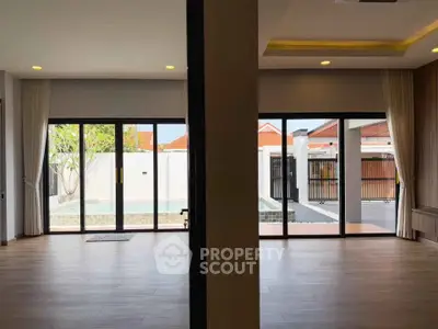 Spacious modern living room with large glass doors opening to a private pool area.