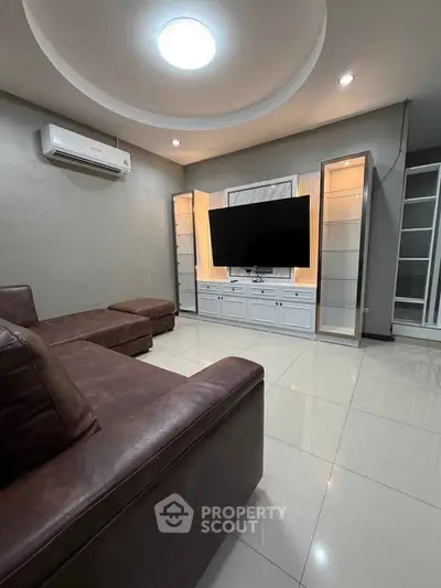 Modern living room with sleek leather sofas and large TV unit, perfect for relaxation and entertainment.