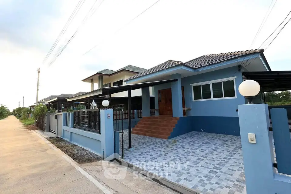 Charming blue single-story house with tiled driveway and welcoming entrance.