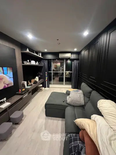 Modern living room with sleek black paneling, cozy sectional sofa, and stylish shelving, perfect for relaxation and entertainment.