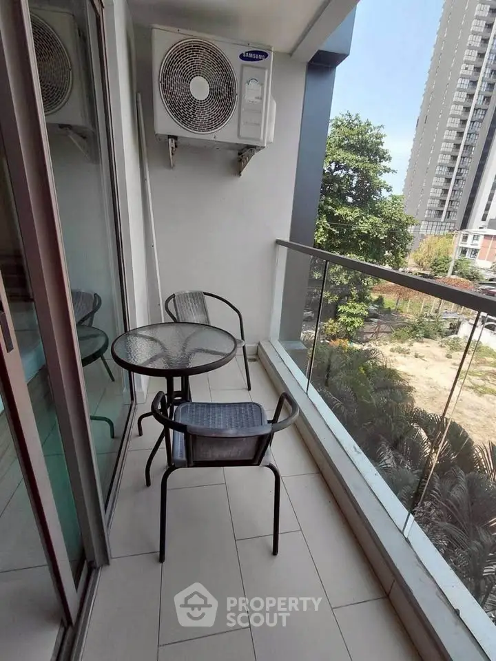 Charming balcony with glass railing and outdoor seating, perfect for relaxation with a view of the cityscape.