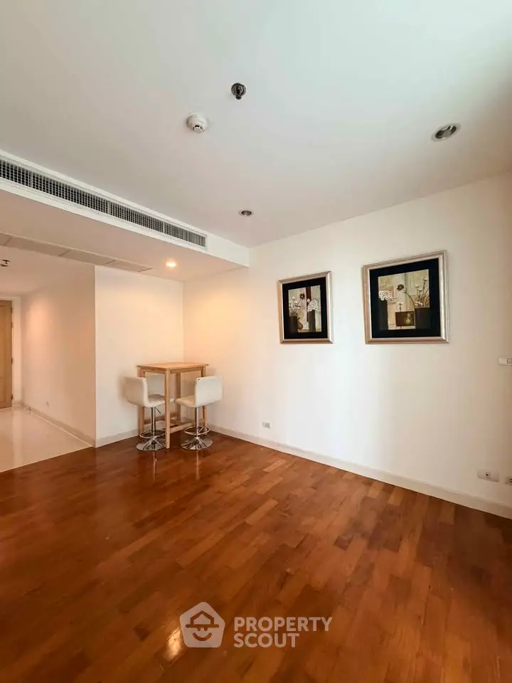 Spacious living room with wooden flooring and modern decor in a stylish apartment.