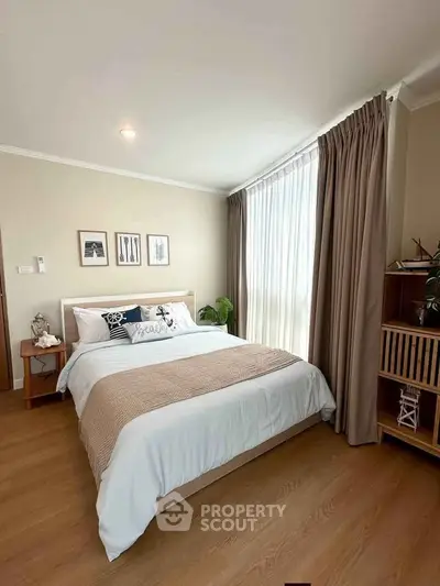 Cozy bedroom with elegant decor and large window, featuring stylish furniture and warm lighting.