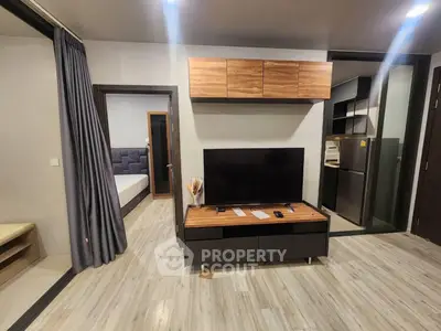 Modern living room with sleek TV stand and wooden accents, adjacent to a cozy bedroom and stylish kitchen.