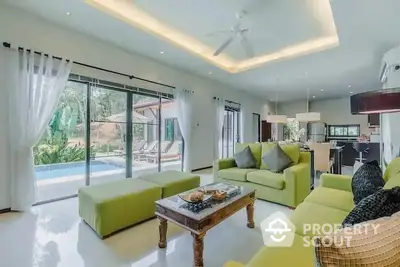 Spacious living room with pool view and modern green sofas in luxury home