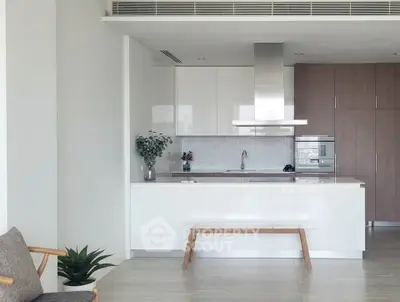 Modern kitchen with sleek white cabinetry and stainless steel appliances in a stylish apartment.