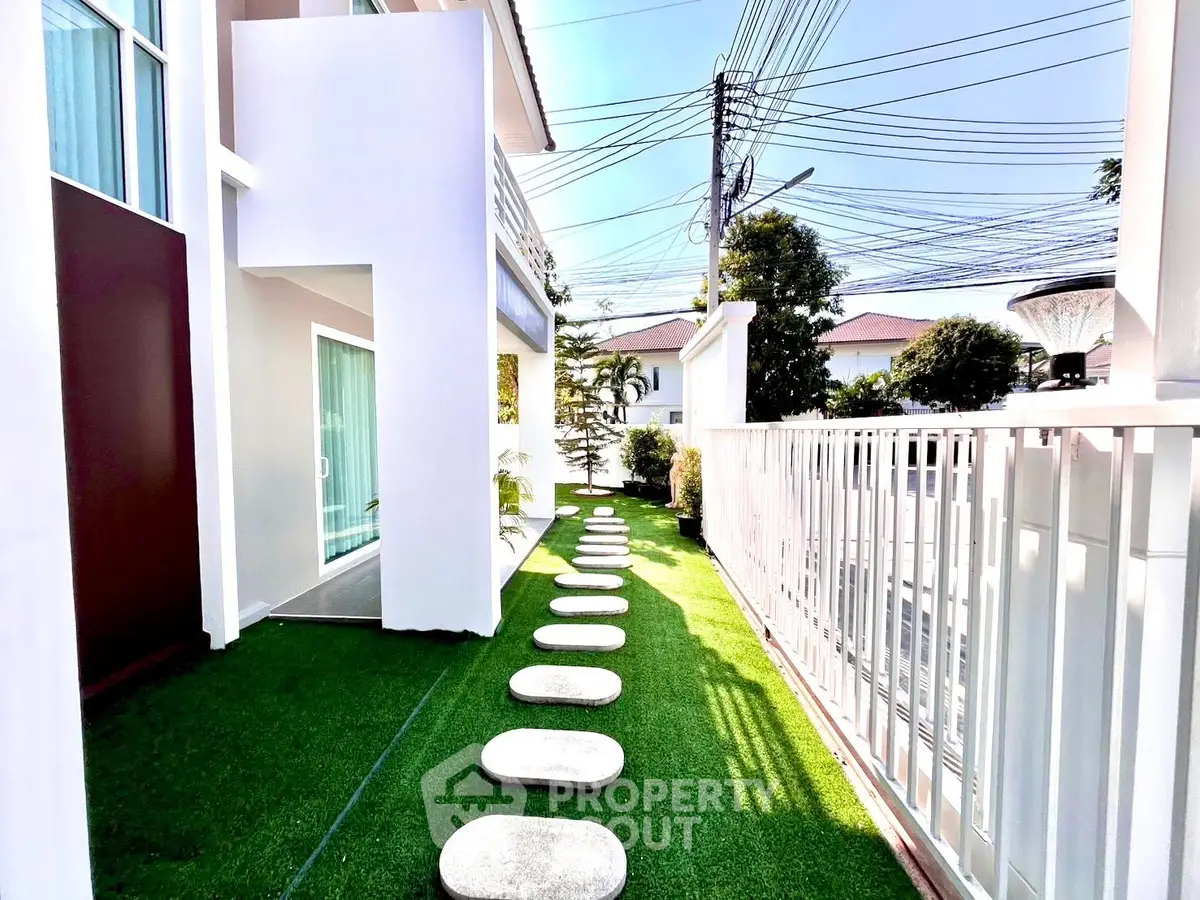 Modern townhouse exterior with lush green garden and stepping stones pathway
