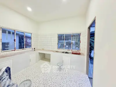 Spacious kitchen under renovation with tiled walls and floors, ample natural light.